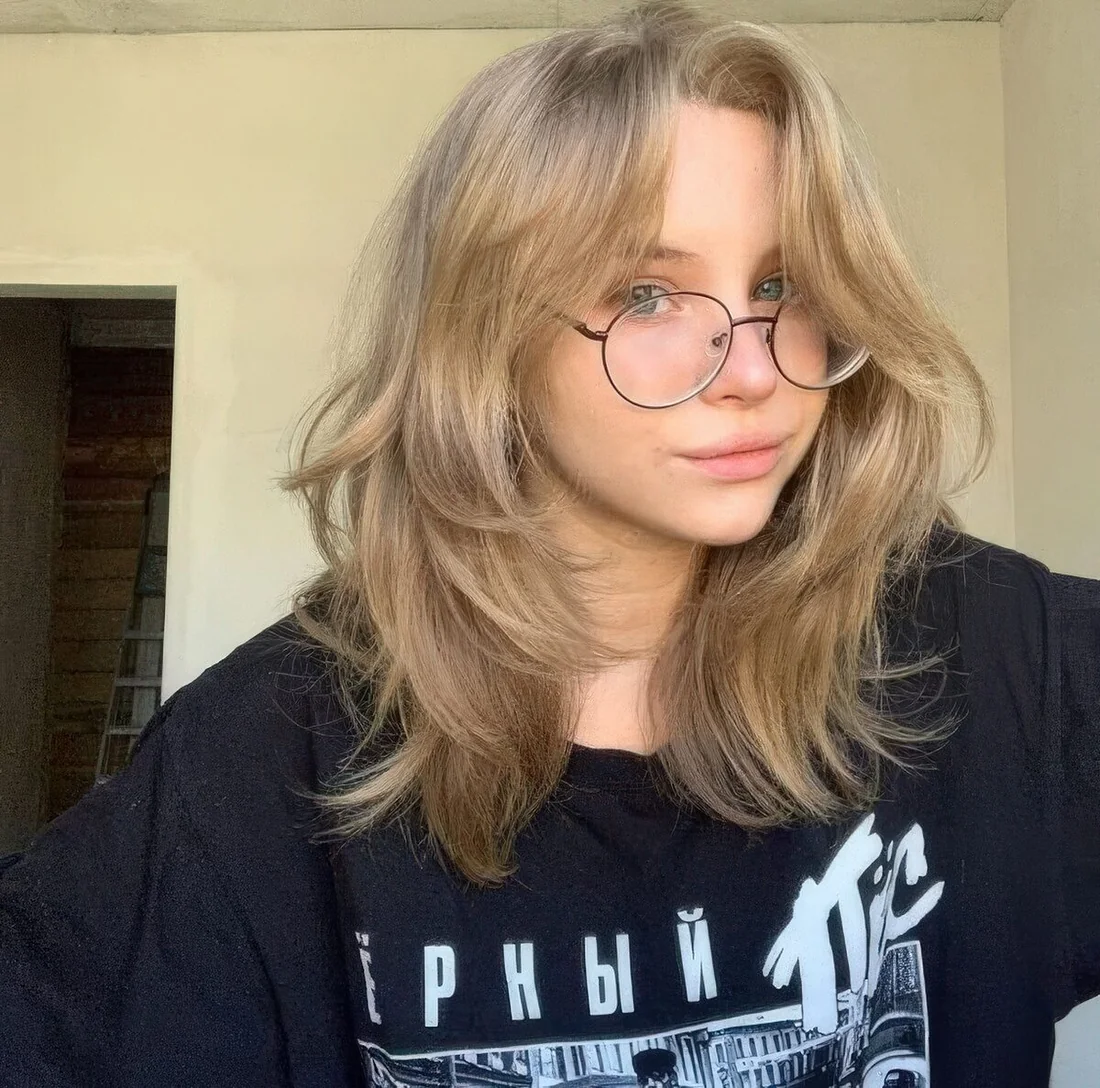 Wolf cut styled with delicate layers, with a soft blonde shade and center part.
