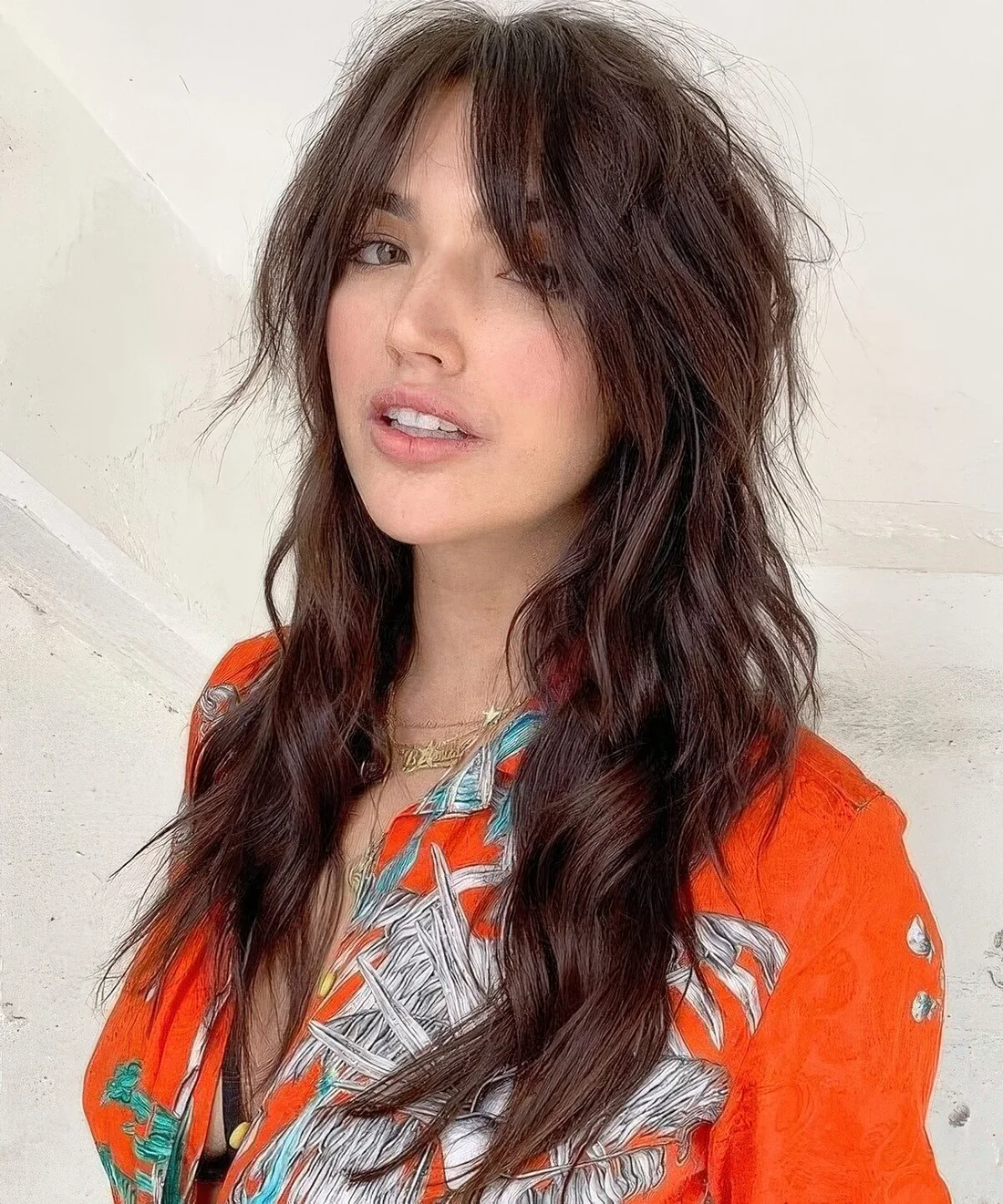 Dark brunette long wolf haircut with bottleneck bangs, waves down and volume.