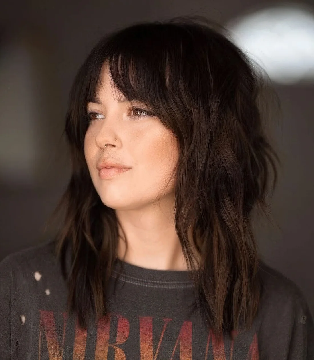 Dark brunette medium wolf cut with bottleneck bangs and messy waves.