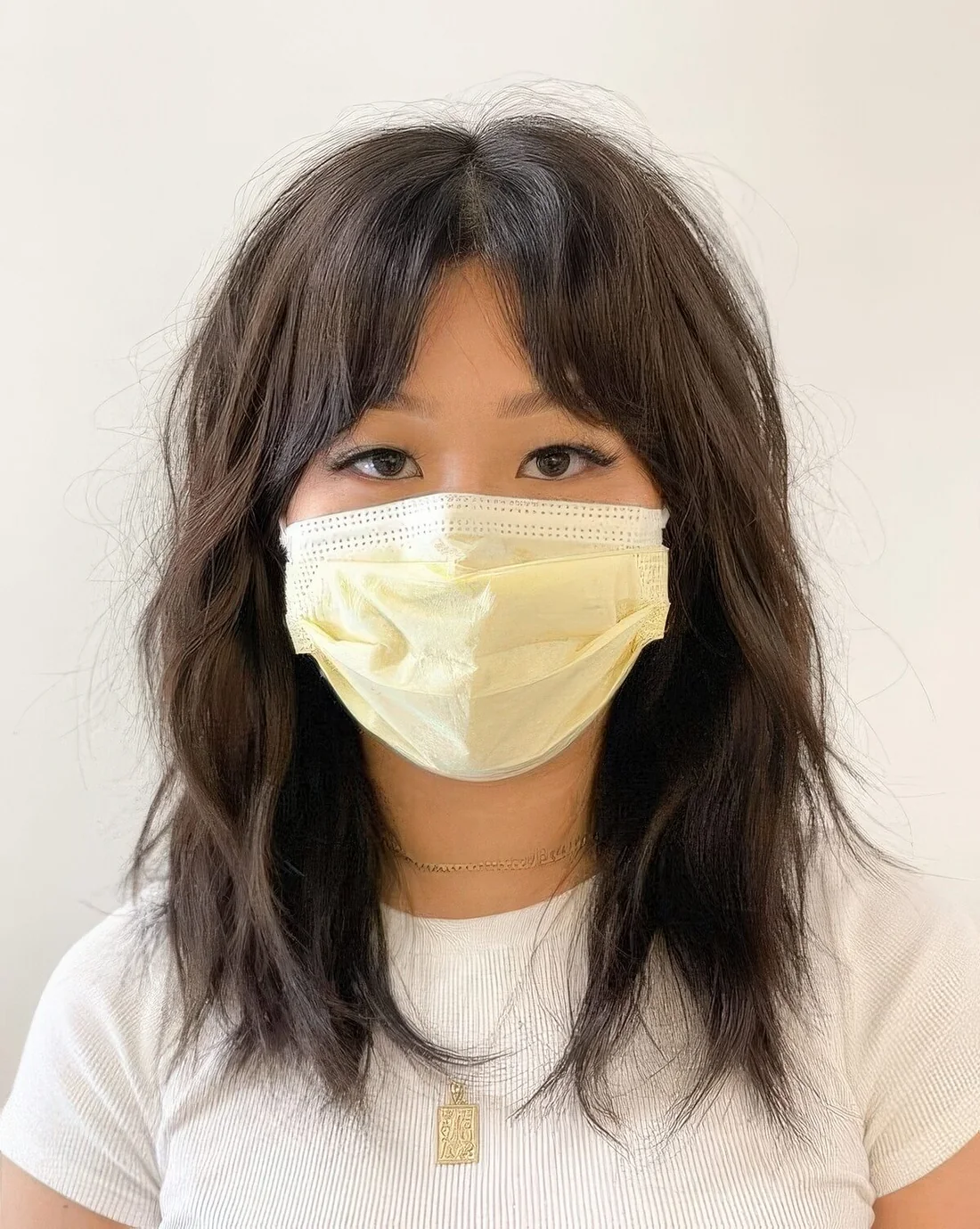 Dark brunette medium wolf cut with bottleneck bangs, wavy and messy hair.