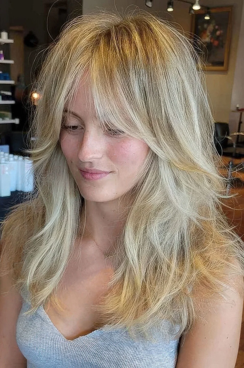 Long blonde wolf haircut with curtain bottleneck bangs, messy waves down.
