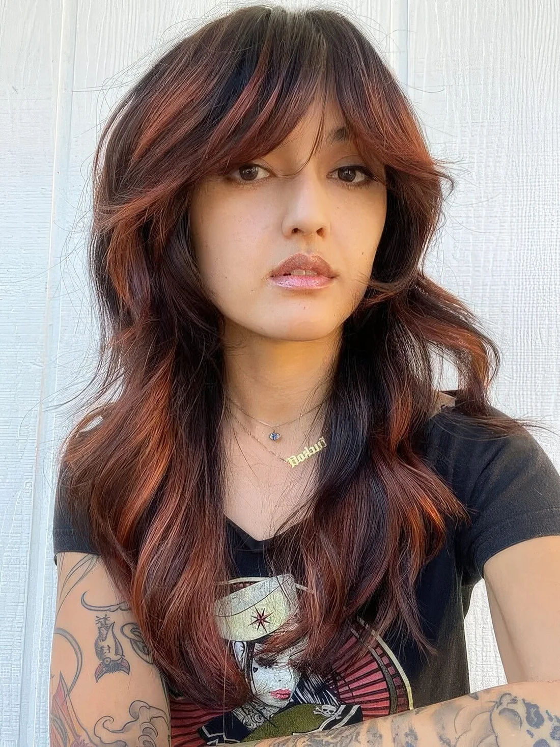 Long black wolf haircut with ginger balayage, bottleneck bangs and waves.
