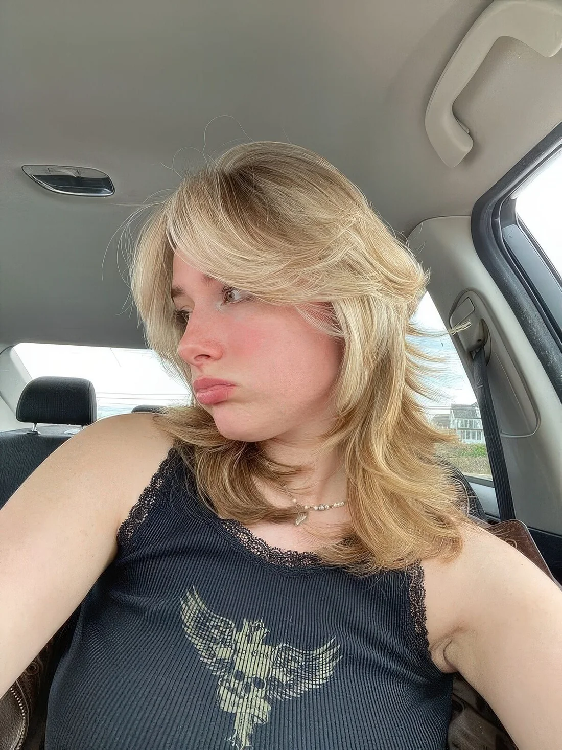 Medium blonde wolf cut with bottleneck and curtain bangs plus waves.