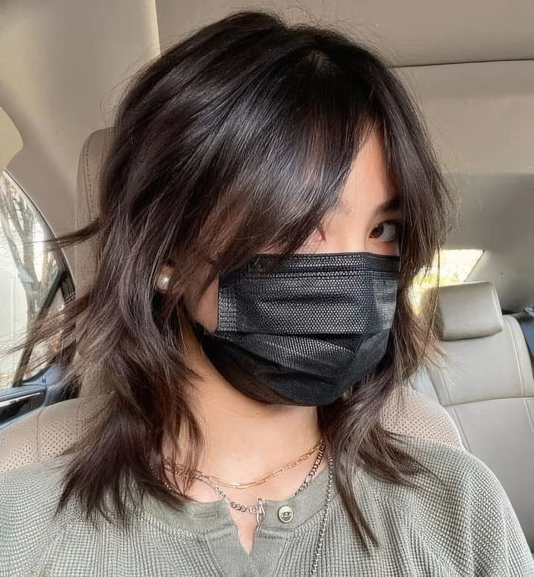 Medium brunette wolf cut with bottleneck bangs and messy shaggy touches.