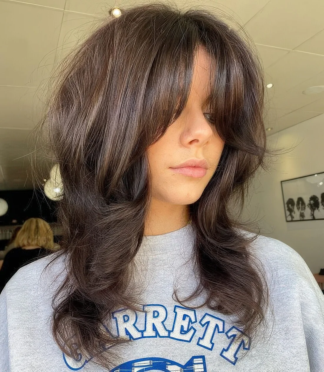 Medium dark brunette wolf cut with bottleneck bangs and a lot of volume and waves.