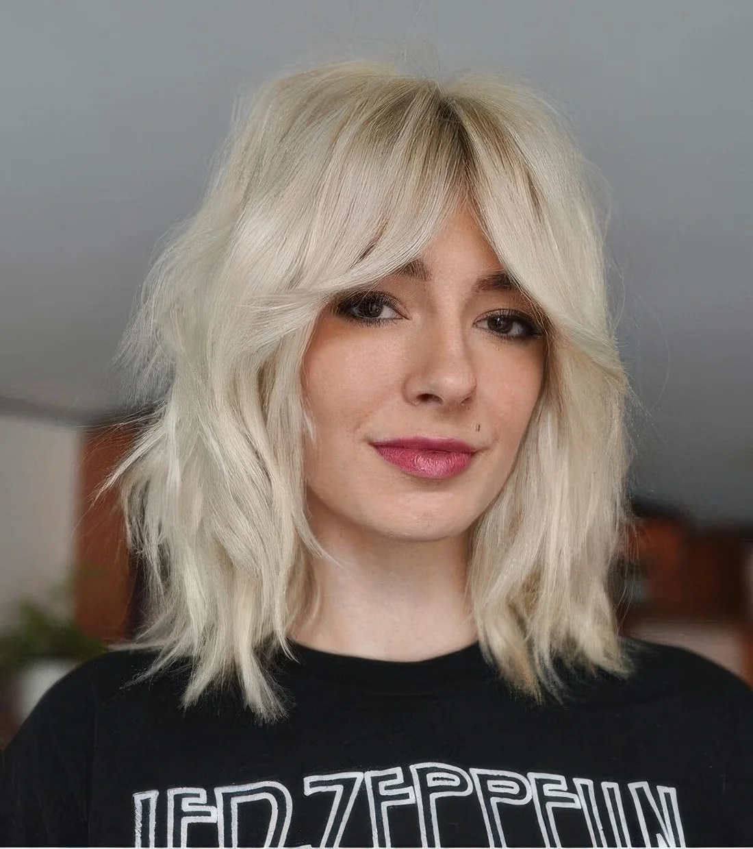 Platinum blonde medium wolf cut with bottleneck bangs and messy texture.