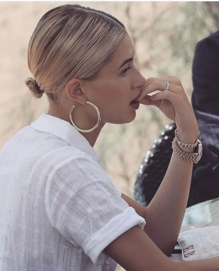 A smooth blonde bob is drawn into a tiny low bun beneath a precise center part