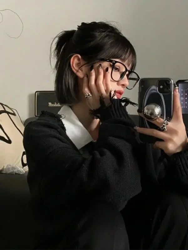 A dark bob with bangs is secured in a small half-up ponytail while the lower length stays loose