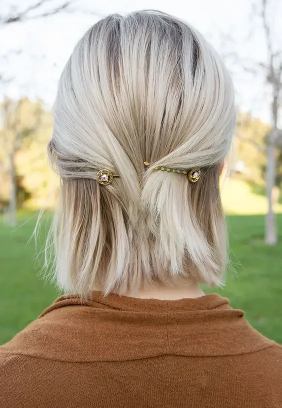 A platinum bob is pinned back symmetrically with two tiny gold hairpins above the ears