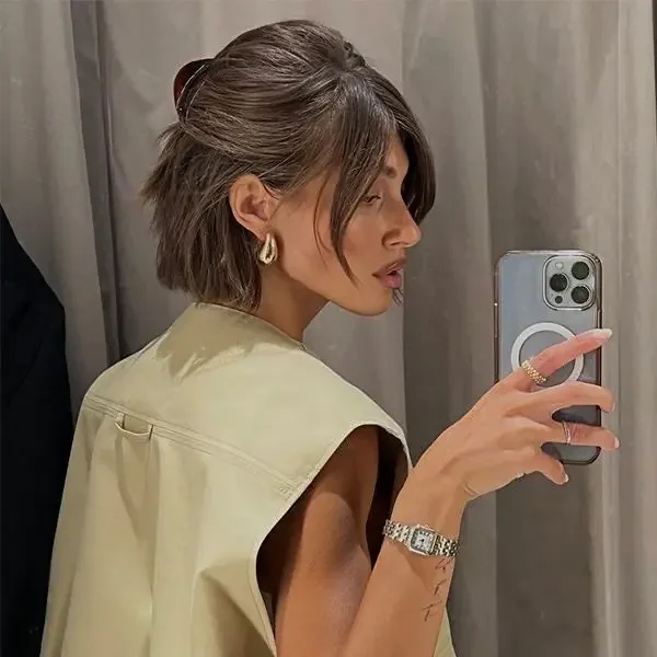A brunette bob is swept back with gentle crown volume and a discreet clip