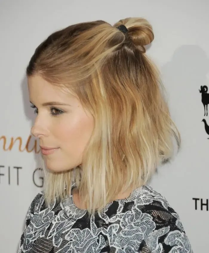A blonde bob is tied into a small high knot while the remaining short layers fall around the shoulders