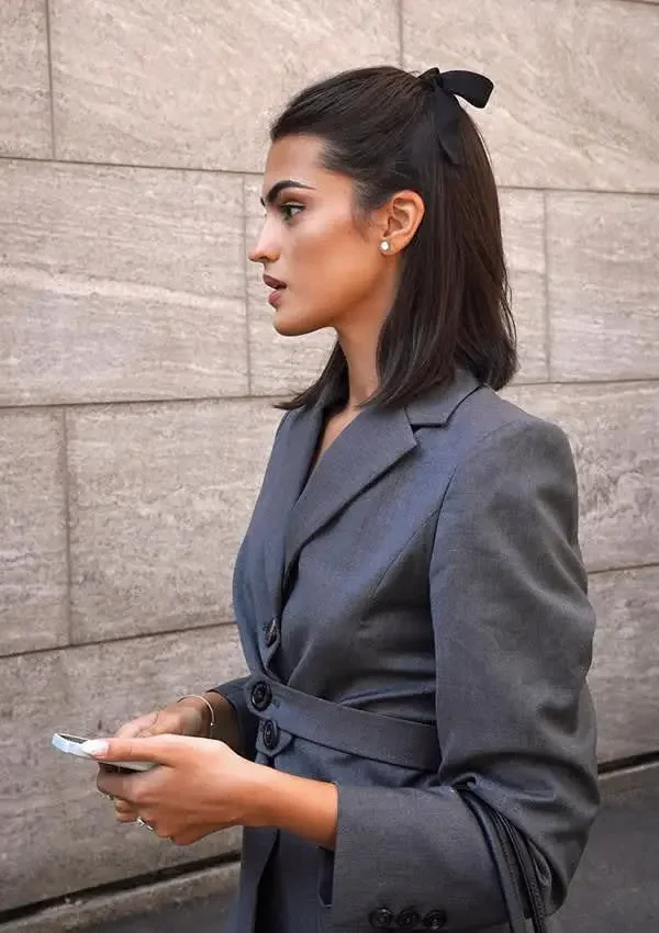 A smooth dark bob is tied half-up with a neat black ribbon bow
