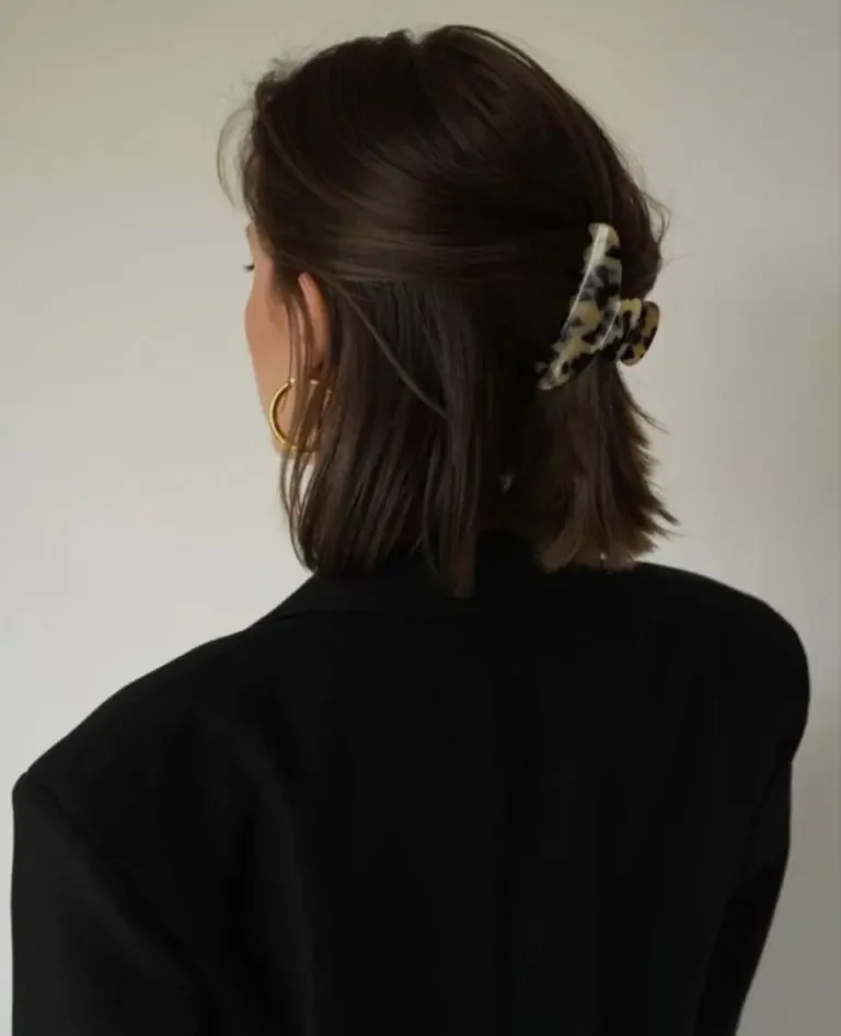 A brunette bob is folded into a low half-up twist and held with a compact claw clip