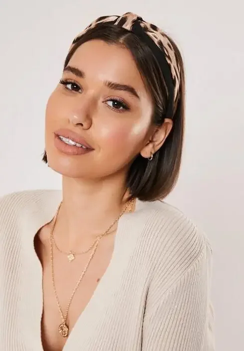 A sleek brunette bob is paired with a slim leopard-print headband and center part