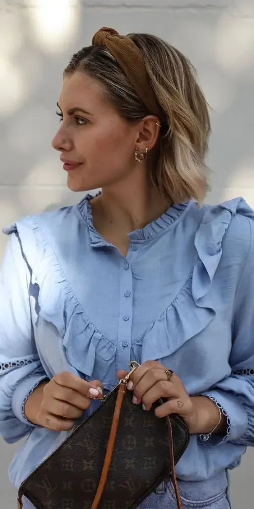 A softly wavy blonde bob is pushed back with a dark padded headband